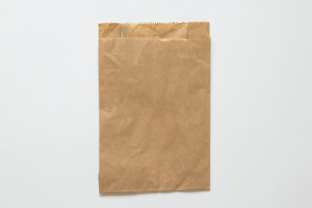 Brown paper bag on white background as mockup, kraft paper packaging, top view, isolated object for products or giftsの写真素材