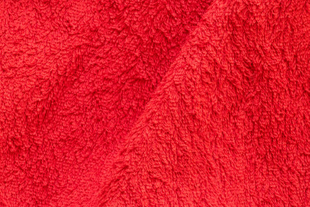 Red terry towel close-up, soft fabric texture with loops, cozy cotton materialの写真素材