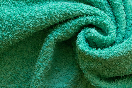 Mint colored terry towel twisted into a spiral close-up, soft texture of fabric with loops, cozy cotton materialの写真素材