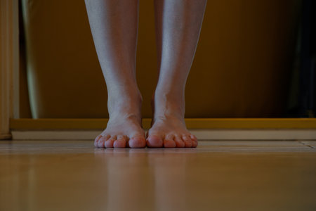Women's bare feet on the floor in the apartment in the hallway, girl's legs