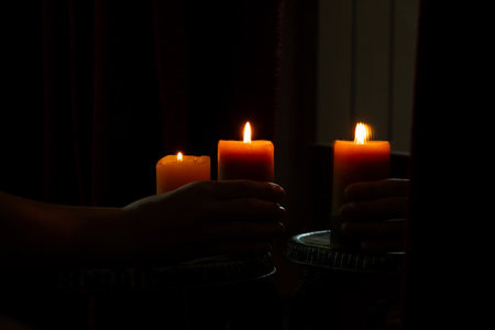 Female hand holding candle near mirror in dark room, burning candleの写真素材