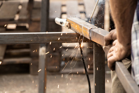 Welding metal parts with sparks and smoke - the work process of a welder joining metal elements with manual weldingの写真素材