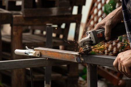 Grinding a weld on metal structures with a grinder, a master working on processing joints after welding outdoorsの写真素材