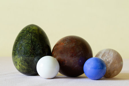 Collection of jasper stones of different colors and shapes, moonstone as a ball, lapis lazuli, onyx on the table, precious stonesの写真素材