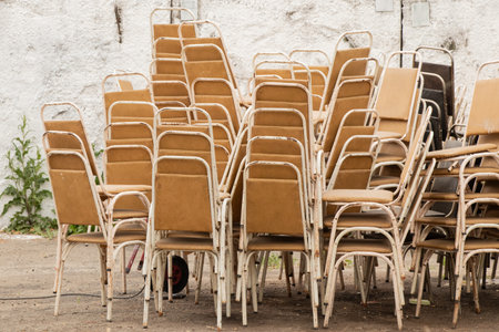 Group of old Soviet metal chairs stacked in a pile on the street near the wall, vintage furniture USSRの写真素材