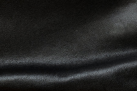 Background of black leather with folds and shadows close-up, women's leather bagの写真素材