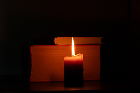 Burning candle next to books in the dark, prayer, bible reading, religion, faith, light,...