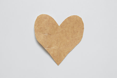 Brown craft paper heart cut with scissors on white background for valentine or love messageの写真素材