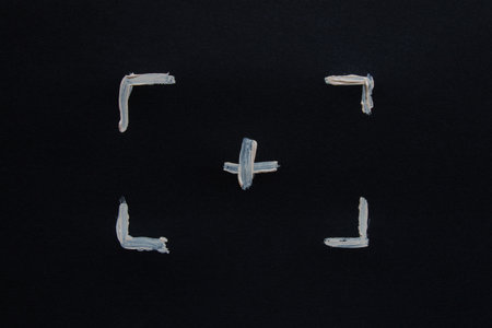 White painted frame and plus sign in the center from corners on black paper as a marking for focusing, scanning, graphic design, photo or video layoutの写真素材