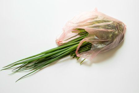 Green onions, parsley and dill in a transparent plastic bag on a white background, fresh herbs for...