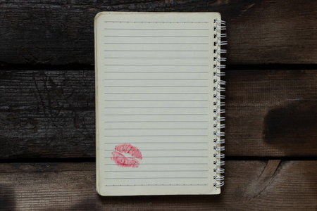 An open notebook with lines on a spiral lies on a wooden table, at the bottom of the page there is a...