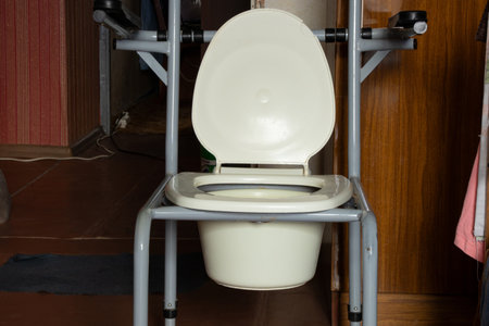Portable toilet for people with limited mobility in an old apartment, plastic seat with a bucket,...