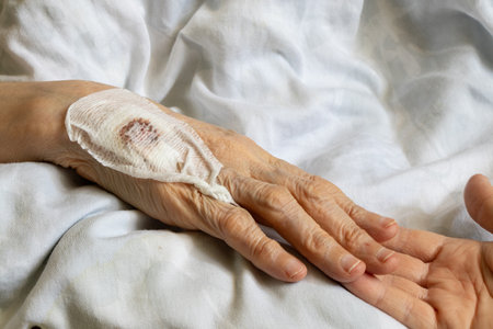 Elderly woman's hand with bloody bandage after injection into vein and hand of young girl as support...