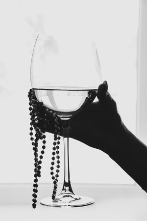 Woman's hand with manicure holding a glass of white wine by the window in a bright roomの写真素材