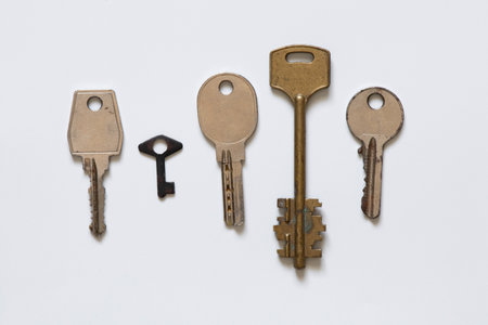 Five metal keys of different shapes and sizes old and arranged in a row on a white background