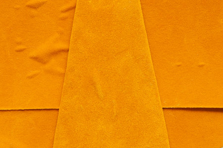 Close-up of orange suede with uneven surface and folds, texture for background or wallpaper