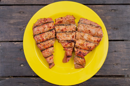 Three tuna steaks cooked on the grill with a crispy crust and cuts and lying on a plastic yellow...