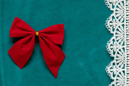 Turquoise velour fabric with a red decorative bow with a gold ring in the middle and white lace on the side, as a decoration or elementの写真素材