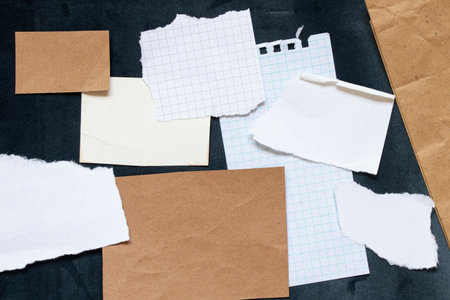 Various scraps and cards of craft paper, white and checkered, are laid out on dark blue velour as a...