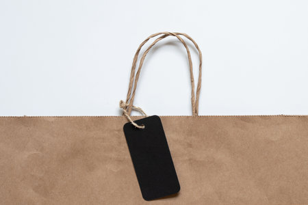 Brown paper bag with handles and black tag and used as a mockup for a price tag or logo in the designの写真素材