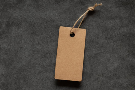 A brown blank tag on a rope lies on a gray fleecy fabric as a mockup for a design close-upの写真素材