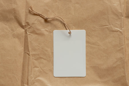 White blank tag on string lies on brown crumpled paper as mockup for design close-upの写真素材
