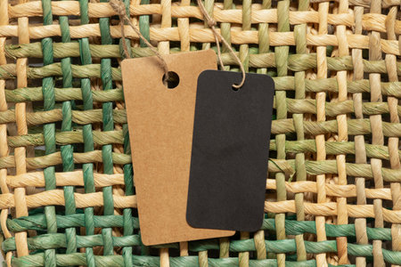 Black empty tag and brown on a rope lie on a wicker straw background as a mockup for designの写真素材
