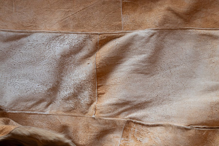 A close-up of a brown suede surface with visible seams. The soft suede texture is suitable as a...