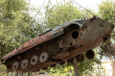 Moving decommissioned military equipment with a crane. A rusty, crewless armored vehicle is lifted...