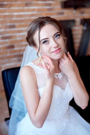 Brown-haired bride with classic wedding hairstyle, smiling taking wedding bouquet in her hands.の写真素材
