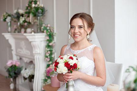 Brown-haired bride with classic wedding hairstyle, smiling taking wedding bouquet in her hands.の写真素材