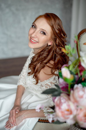 Portrait of beautiful red-haired girl sitting, smiling on big arm-chair.の写真素材