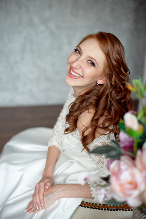 Portrait of beautiful red-haired girl sitting, smiling on big arm-chair.の写真素材