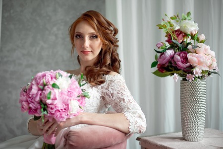 Portrait of beautiful red-haired girl sitting, smiling on big arm-chair.の写真素材
