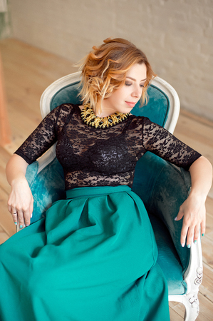 Image of elegant girl sitting in retro style armchair. Redhaired curly young model.の写真素材