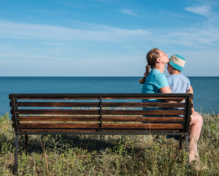 Young mother with child sitting on the bench near the sea ocean.の写真素材