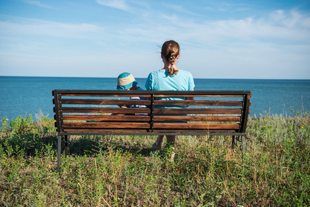 A beautiful woman wuth child looking to the sea in front of the beautiful ocean and sky view.の写真素材