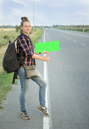 A beautiful young tourist girl, smiles, catches a hitchhiker. Concept: to travel the world, holidays, people, vacations.の写真素材