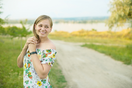 Half length portrait of charming positive woman dressed in long white summer dress happy smiling in sunset background.の写真素材