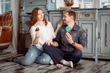 A young couple holding cakes while looking to each other. The girl is surprised.の写真素材