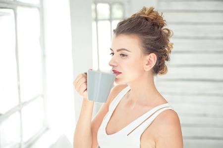 Pretty young woman holding a cup of coffeeの写真素材