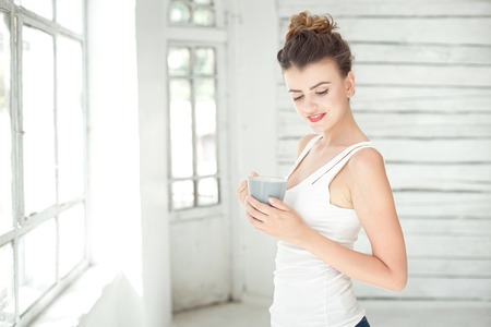 Pretty young woman holding a cup of coffeeの写真素材