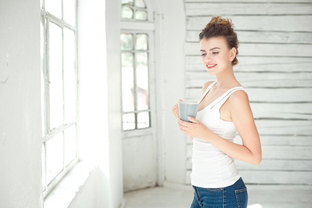 Pretty young woman holding a cup of coffeeの写真素材