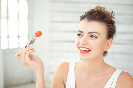 Beautiful girl holding up cherry tomatoの写真素材