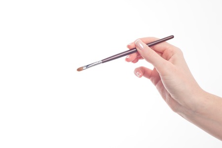 Female hand holding professional make-up brushe isolated on white backgroundの写真素材