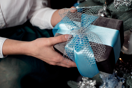 woman hands holding Christmas gift wrapped with blue ribbonの写真素材