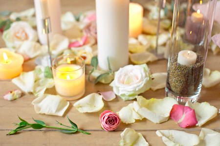Spa, health, beauty and wellness concept with rose petals scattered around burning candles on a wooden floor in a high angle viewの写真素材