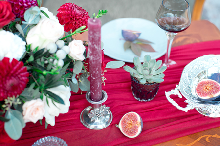 Small succulent alongside a candle on a formal table setting viewed from above on a red tableclothの写真素材