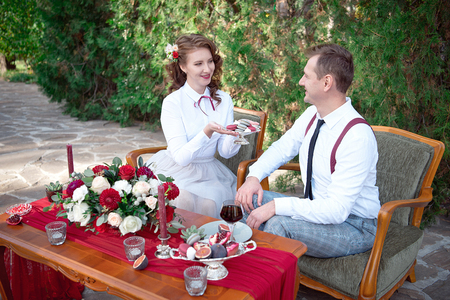 Romantic table with fresh flowers and candles with couple in love on background.の写真素材