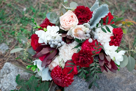 Romantic arrangement of red and white summer flowers with roses and dahlias on stonesの写真素材